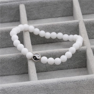 Detail van witte kralenarmband met yin yang bedeltje in een grijze juwelendoos