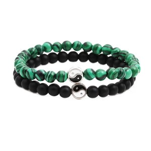 Matching turquoise and lava stone bracelets with yin yang charms on a white background