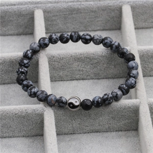 Macro-opname van Yin Yang-bedel op zwarte obsidiaan kralenarmband op een dienblad