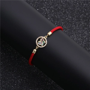 Detailed macro of red cord bracelet with gold butterfly charm and zircon inlay