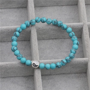 Detailweergave van de Yin Yang kralenarmband met turquoise blauwe stenen en een tai chi bedel