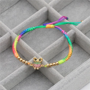 Detail of colorful woven bracelet with gold owl charm and micro-inlaid colored zircons