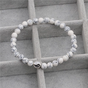 Macro-opname van witte turquoise kralenarmband met een zilveren Tai Chi Yin Yang bedeltje