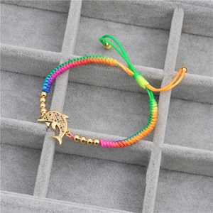 Close-up of dolphin charm with colorful zircons on braided adjustable rainbow bracelet