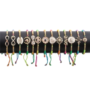 Detailed close-up of 13 colorful braided bracelets with gold charms and zircon stones