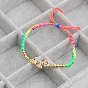 Detailed macro of a woven rainbow bracelet with a zircon-encrusted seahorse charm