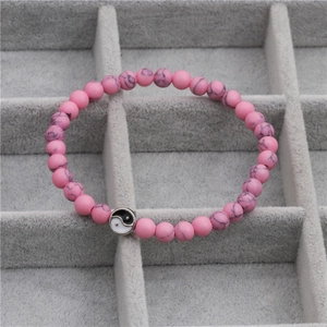 Detail van roze marmeren kralen en zilveren Yin Yang bedeltje op de stenen kralenarmband