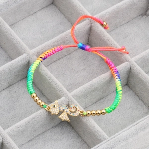 Detail of colorful woven rope bracelet with gold cat charm and inlaid cubic zirconia