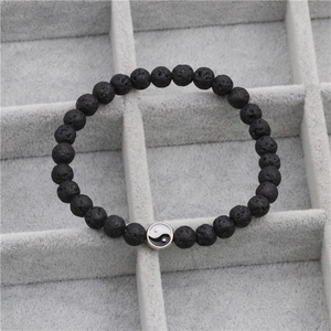 Detail van vulkanische steen kralenarmband met een zilveren Yin Yang symbool bedel