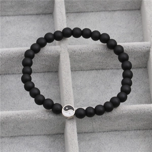 Macro detail van zwarte matte lavasteen kralen en zilveren Tai Chi Yin Yang bedelarmband