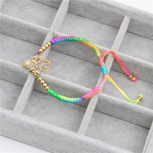 Close-up of woven rainbow bracelet with gold octopus charm and sparkling zircons
