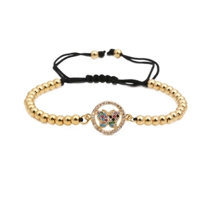 Macro shot of colorful zircon butterfly charm and golden beads on woven bracelet