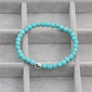 Macro detail van turquoise kralenarmband met Yin Yang bedeltje op een sieradentray
