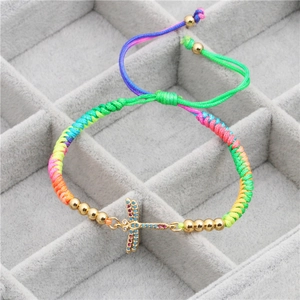 Macro detail of rainbow woven rope bracelet with dragonfly charm and zircon accents
