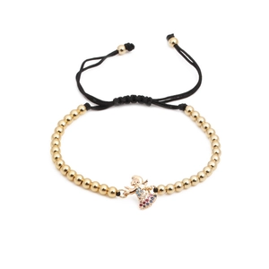 Detailed macro view of woven gold bead bracelet featuring a colorful zircon angel charm