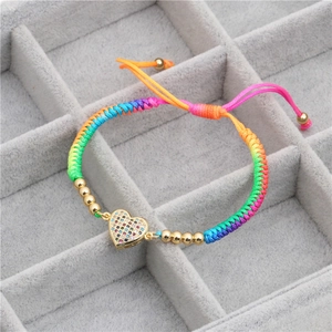 Handmade rainbow braided bracelet with zircon heart charm and golden beads in a grey jewelry box