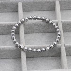 Detailweergave van de kralenarmband met gepolijste zeshoekige kralen en Tai Chi hanger