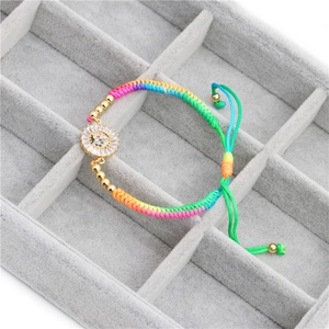 Detail of colorful braided rope bracelet with a gold zircon-inlaid circular charm