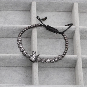 Detailed macro view of woven bracelet with zircon crown charm and grey metal beads