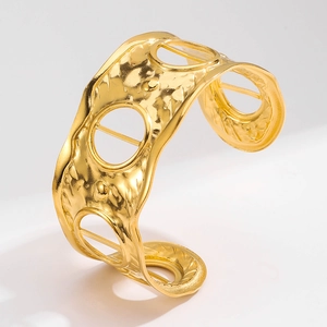 Macro detail of wide gold stainless steel cuff bracelet with hammered texture and hollow dots