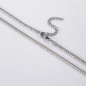 Detailed macro view of a silver stainless steel wheat chain with a lobster clasp closure
