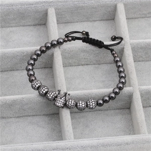 Macro shot of crown bracelet detailing micro-paved cubic zirconia balls and woven cord