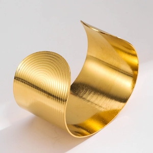 Macro view of wide gold cuff bracelet featuring concentric circular groove textures