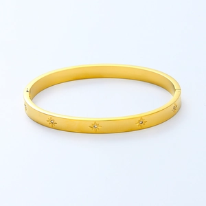 Macro detail of gold starburst bangle with zircon insets and a secure hinge closure