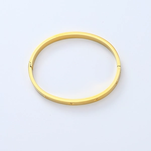 Detailed close-up of gold-plated stainless steel bangle with engraved star patterns and zircons