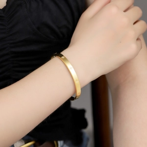 Detail of a slim gold stainless steel bangle with engraved stars and small zircons