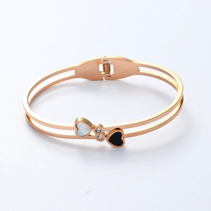 Détail des éléments cœur avec nacre et émail noir sur le bracelet jonc en or rose poli