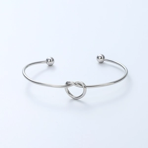 Polished silver knot open bangle featuring heart-shaped design and smooth metal ball ends
