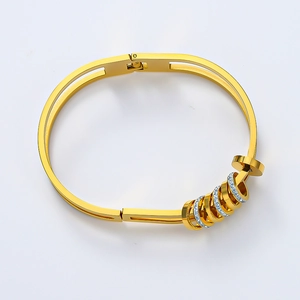 Detail eines 18K vergoldeten Titanarmbands mit gleitenden Ringen und weißen Kristallen