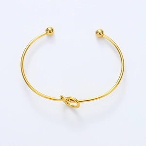 Detailed view of a gold knot cuff bangle with smooth polished surface and end beads