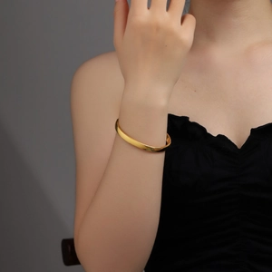 Minimalist 6mm gold-tone titanium steel domed bangle shown on a model's wrist
