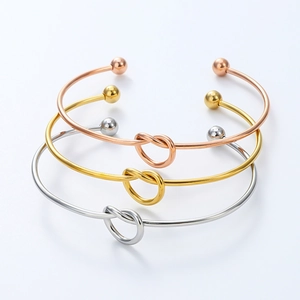 Detailed trio of knotted stainless steel bracelets in rose gold, gold, and silver finishes