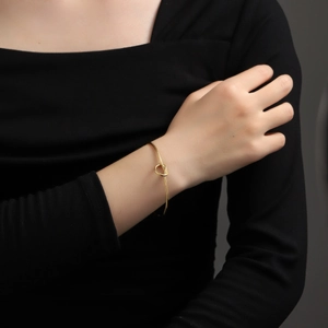 Polished rose gold knot bangle for women featuring a minimalist heart-shaped knot design