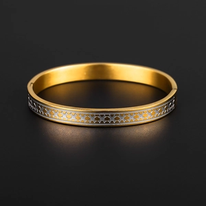 Titanium steel bangle with two-tone gold plating and geometric star patterns on black background