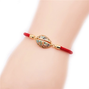 Red braided rope bracelet featuring a gold shell charm with colorful zircon stones
