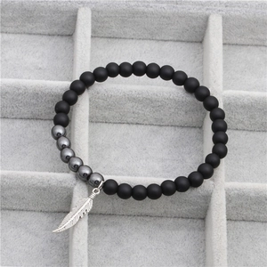 Vue macro détaillée de perles noires mates avec pendentif plume argenté sur velours