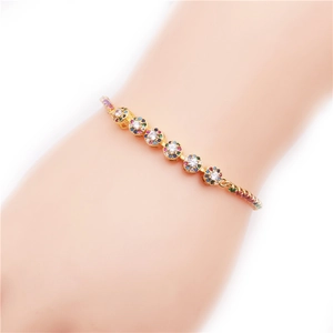 Gros plan d'un bracelet doré orné de zircons multicolores porté sur le poignet