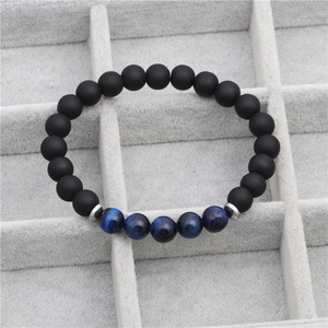 Gros plan de perles d'agate noire mate de 8mm et d'oeil de tigre bleu sur plateau