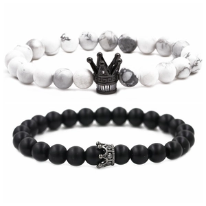 Detalle de pulseras de cuentas de mármol blanco y negro mate con dijes de corona
