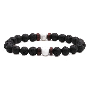 Minimalistisches Armband aus schwarzem Lavastein mit weißen Türkisperlen auf weißem Grund