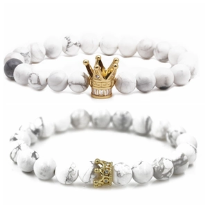 Detalle de las pulseras de cuentas de howlite blanca con dijes de corona dorada y piedras