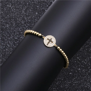 Golden beaded cross bracelet with black pavé stones and sparkling zircon crystals