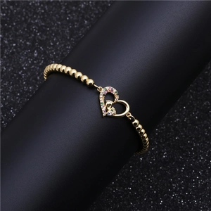 Bracelet à billes dorées avec breloque cœur sertie de zircons colorés et motif d'empreinte
