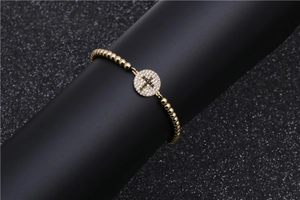 Gold-plated beaded cross bracelet with micro-paved zircons on a round charm