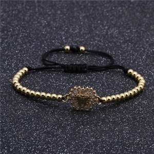 Makro-Detail eines geflochtenen Armbands mit Goldperlen und Zirkonia-Schmetterling