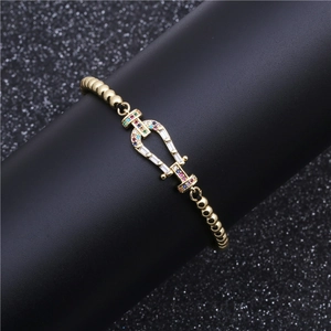 Golden beaded bracelet with horseshoe clasp and multicolored cubic zirconia stones